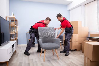 İki Genç Erkek Nakliyeci Oturma Odasında Plastik Paketlenmiş Mobilya Paketi