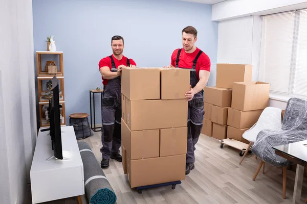 Leende Professionella Movers Uniform Med Stapel Kartonger Vardagsrummet — Stockfoto