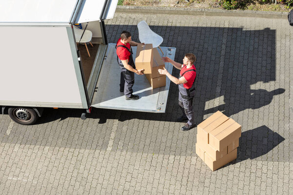 An Overhead View Of A Male Movers Unloading The Cardboard Boxes Form Truck On Street
