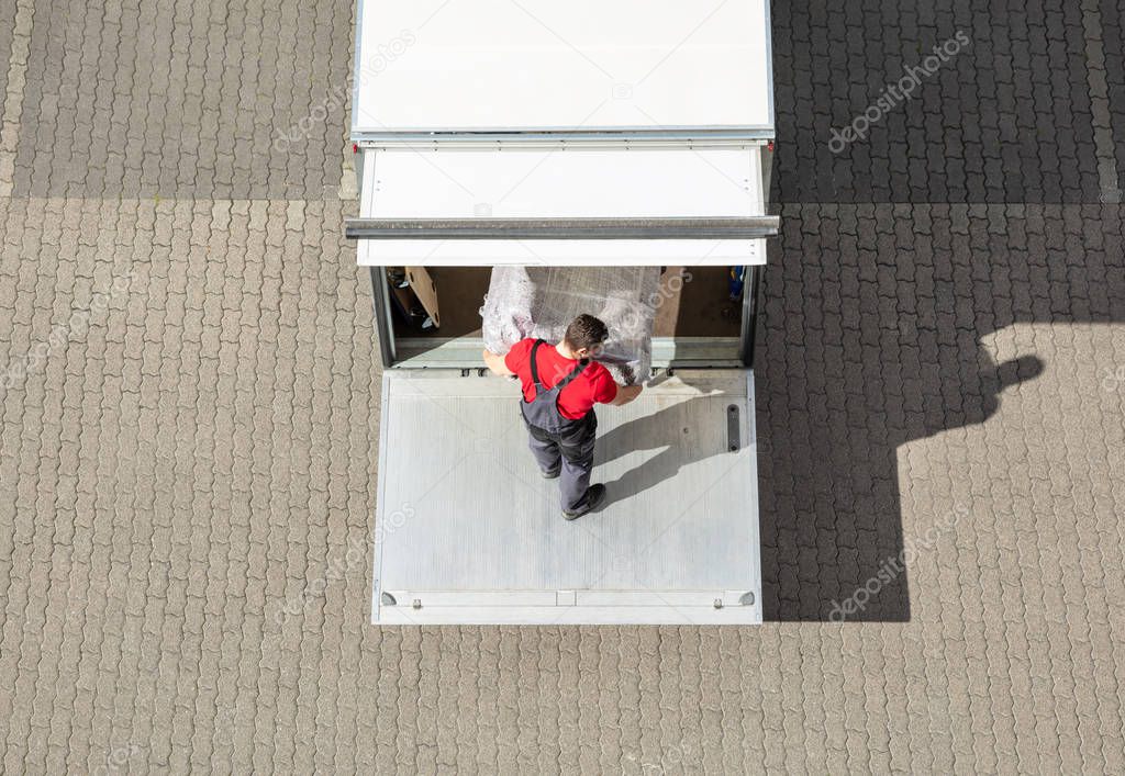 An Elevated View Of Male Mover Unloading The Furniture From Truck On Cobblestone Pavement