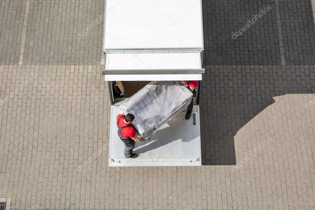 An Elevated View Of Male Mover Unloading The Furniture From Truck On Cobblestone Pavement