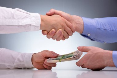 İş adamlarının el sıkışarak anlaşmayı imzalaması ve rüşvet almaları yakın plan.