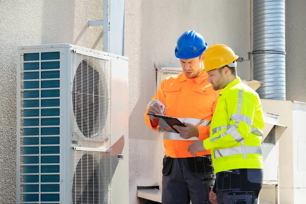 Dois Eletricistas Homens Vestindo Jaquetas Segurança Verificando Unidade Condicionado Telhado — Fotografia de Stock