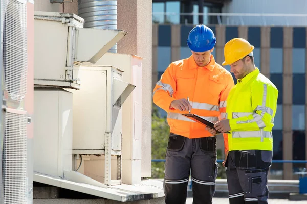 Två Elektriker Män Bär Skyddsvästar Kontrollerar Luftkonditioneringsenheten Taket — Stockfoto