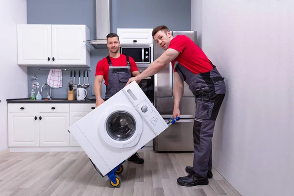 Dos Jóvenes Hombres Profesionales Mueven Uniforme Colocando Lavadora Moderna Cocina — Foto de Stock