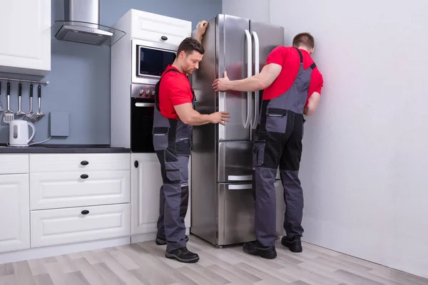 Dos Hombres Jóvenes Mueven Uniforme Que Coloca Refrigerador Moderno Acero —  Fotos de Stock