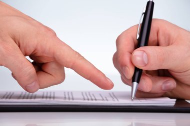 Müşterinin sözleşmeyi kâğıt üzerinde kalemle imzalamasına izin veren birinin yakın plan fotoğrafı.