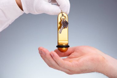 Bir Resepsiyonistin Eli 'nin Gri Arkaplanda Müşteriye Kapı Anahtarı Verdiği Yakın Çekim