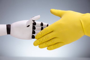 Sarı Eldiven Giyen, Gri Arkaplanda El sıkışan Robot ve Hizmetli 'nin Yakın Çekimi