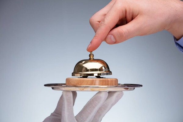 Close-up Of A Person's Hand Ringing Service Bell Hold By Butler