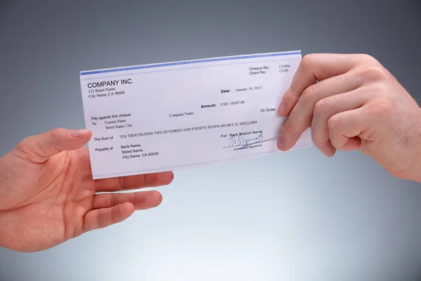 Close Businessperson Giving Cheque Colleague Grey Background — Stock Photo, Image