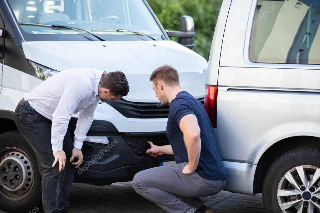 Close-up Of Two Men Inspecting The Car Damage After Accident For The Insurance Claim