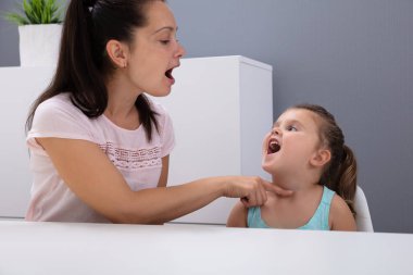Çekici bir kadın konuşma terapisti, ofisteki sesleri nasıl telaffuz edeceğine yardım eder.