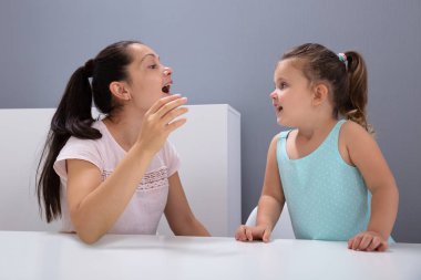 Çekici bir kadın konuşma terapisti, ofisteki sesleri nasıl telaffuz edeceğine yardım eder.