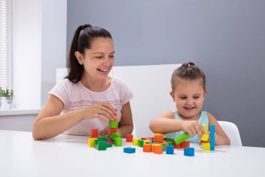 Gülümseyen çocuk yuvası işçisi Beyaz Masada Çocuk Yığını Blokları Oynuyor