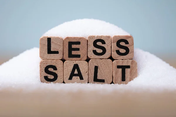Weniger Salz Wort Mit Salz Auf Holztisch Bedeckt — Stockfoto