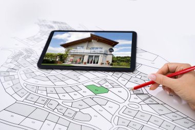 Hand Holding Pencil Over Cadastre Map New Tablet With House Photo clipart