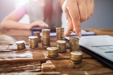 Ahşap masadaki istiflenmiş paraların hesabını yapan kişi. Gelir Vergisi Konsepti