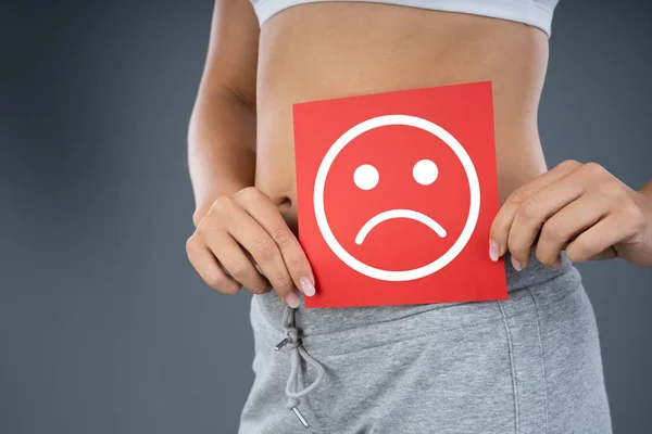 Woman With Stomach Pain Showing Sad Sign On Red Piece Of Paper