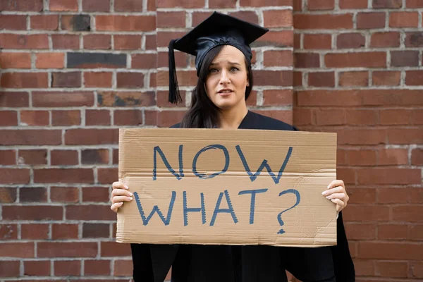 Sad Graduate Student Står Med Vad Placard Mot Tegelvägg — Stockfoto