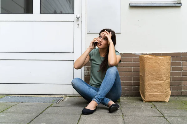 Rädd Ung Kvinna Som Sitter Utanför Dörren Pratar Mobiltelefon — Stockfoto