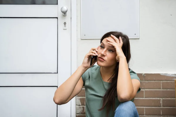 Een Bang Jonge Vrouw Zitten Buiten Deur Praten Mobilalarmtoestel — Stockfoto