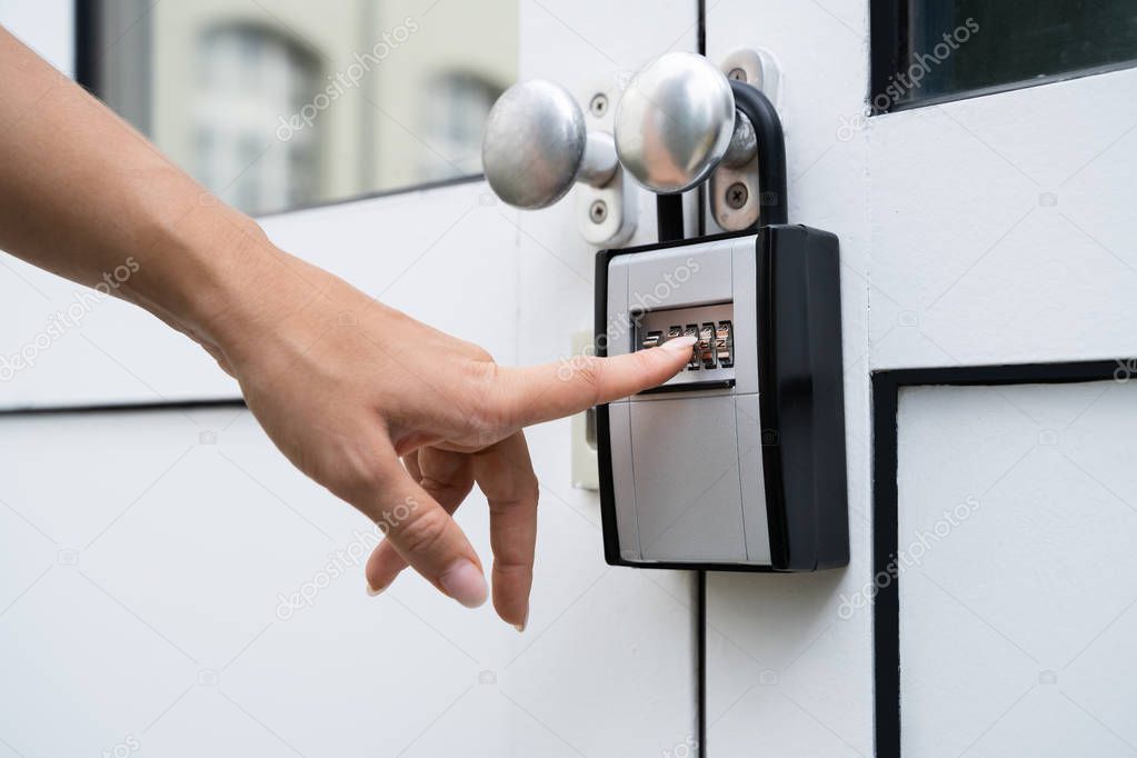 Woman Using Key Safe To Retrieve Keys From House