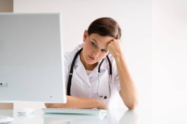 Hüsrana uğramış, çok çalışan, bilgisayardaki üzgün doktor hastanede.