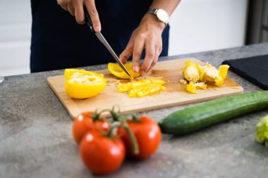Kadın evde yemek pişiriyor, sebze kesiyor.