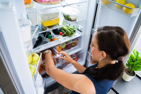Women Looking For Food Inside Fridge In Kitchen