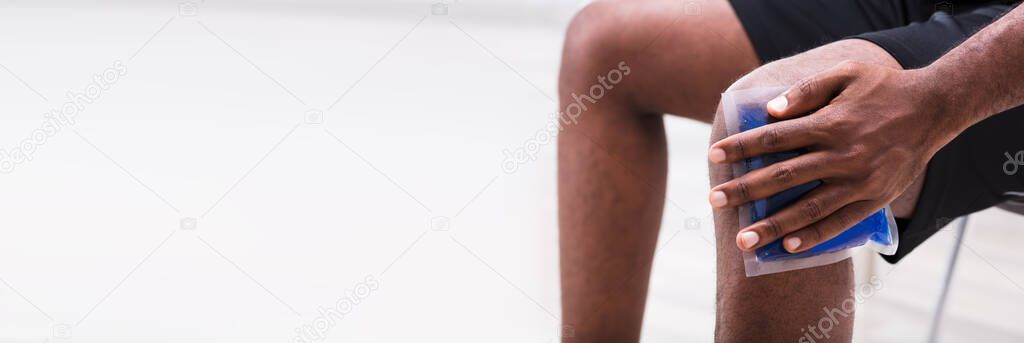 Man Applying Ice Pack Gel On Injured Knee