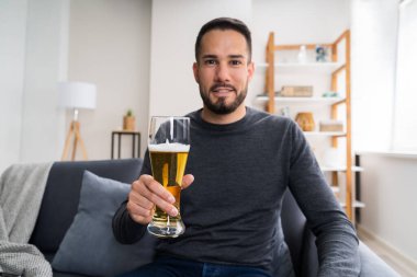 Evde yalnız başına içki içen bir adam.