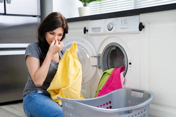 若い女性は台所で洗濯機から臭い服を見て — ストック写真