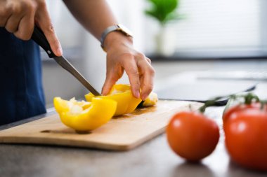 Kadın evde yemek pişiriyor, sebze kesiyor.