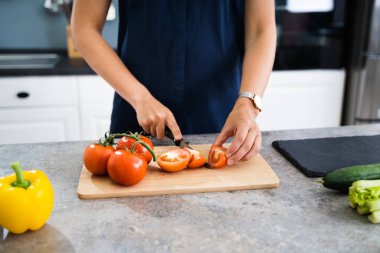 Kadın evde yemek pişiriyor, sebze kesiyor.