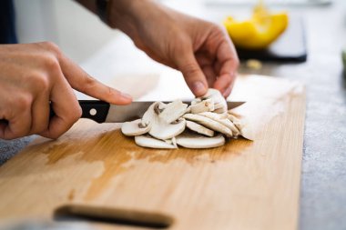 Kadın evde yemek pişiriyor, mantar kesiyor.