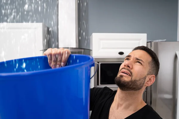 Homem Preocupado Segurando Balde Enquanto Gotas Água Vazam Teto Cozinha — Fotografia de Stock