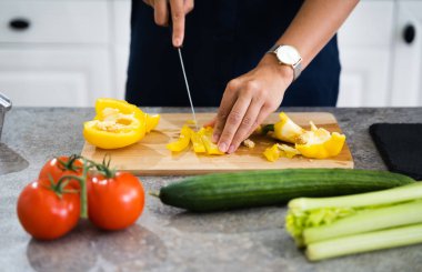 Kadın evde yemek pişiriyor, sebze kesiyor.