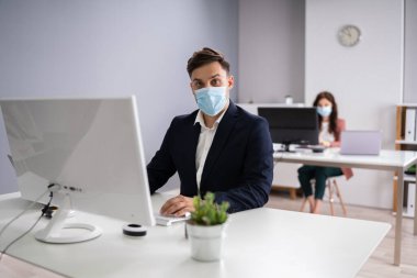 Ofisteki İş Çalışanları Tıbbi maske takıyor ve Sosyal Mesafe Protokollerini izliyorlar