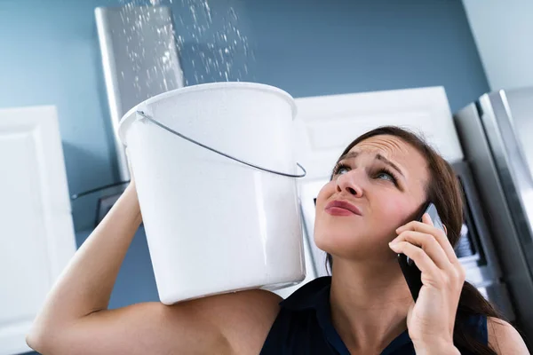 Besorgte Frau Hält Eimer Während Wassertropfen Aus Decke Küche Austreten — Stockfoto