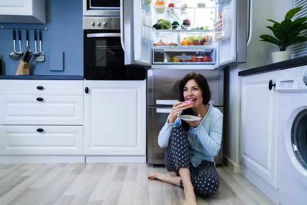 Open Night Sweet Indulgence. Woman Eating Near Refrigerator