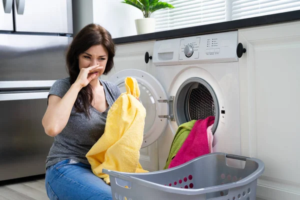 Jovem Mulher Olhando Roupas Fedorentas Fora Máquina Lavar Cozinha — Fotografia de Stock