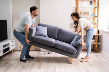 Çift taşınıyor ve mobilya veya kanepe taşıyor.