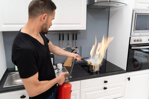 Man Using Fire Extinguisher Stop Fire Burning Cooking Pot Kitchen — Stock Photo, Image
