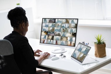 İş kadını, ofis içi güvenlik kamerası görüntülerini işyerindeki bilgisayardan izliyor.