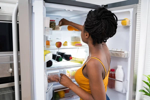 オープン冷蔵庫や冷蔵庫の近くにアフリカ系アメリカ人女性 — ストック写真