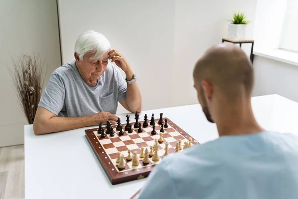 Oudere Senior Schaken Met Verzorger Thuis — Stockfoto