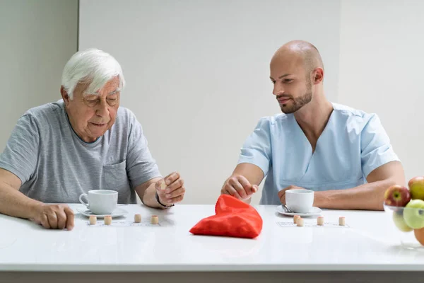 Oudere Senior Spelen Lotto Met Verzorger Thuis — Stockfoto