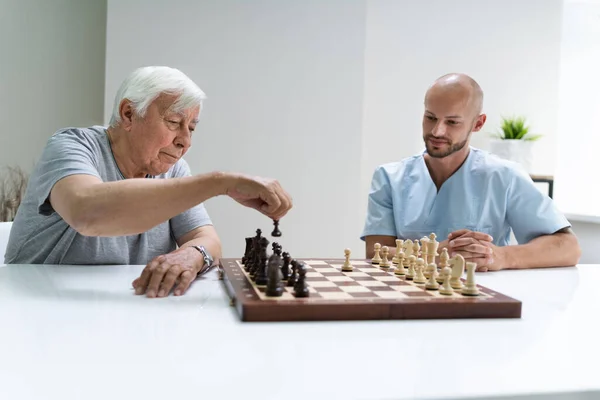 Starší Starší Lidé Hrají Šachy Pečovatelem Doma — Stock fotografie