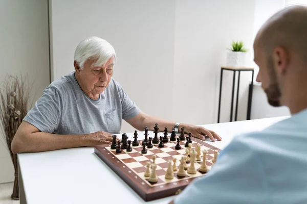 Oudere Senior Schaken Met Verzorger Thuis — Stockfoto